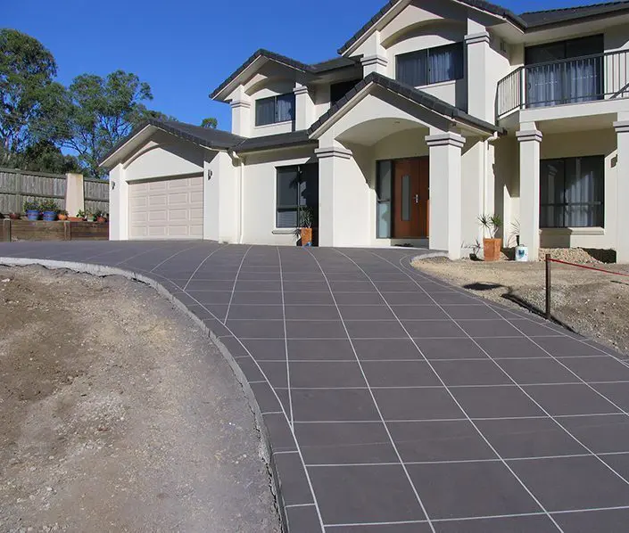 Charcoal tile-pattern driveway restored in front of a rendered two-storey home