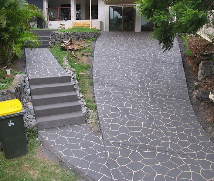 Charcoal flagstone-pattern concrete path and steps beside a garden
