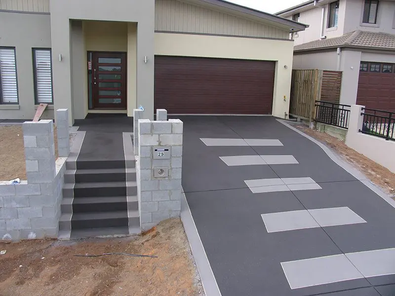 Charcoal driveway with light rectangular inlays leading to rendered entry steps