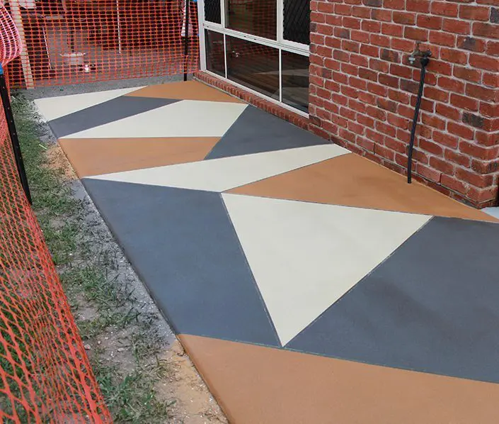 Geometric colour panels in charcoal, tan and cream on an outdoor concrete area