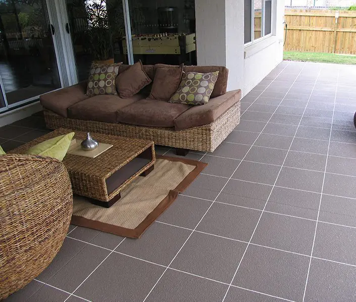 Grey tile-pattern decorative resurfacing on a covered alfresco area with lounge setting